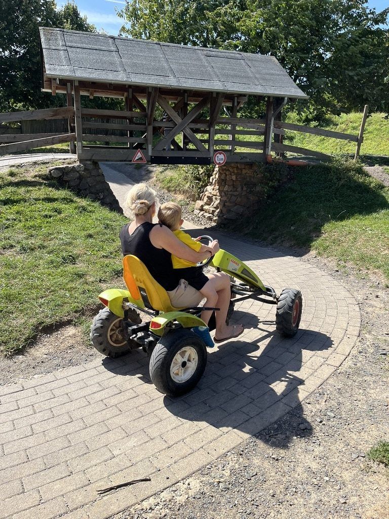 Mutter und Kind fahren Kettcar auf der Bahn am Glessener Mühlenhof