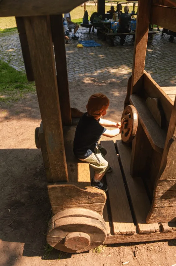 Kind sitzt in einem großen Holzboot auf dem Spielplatz