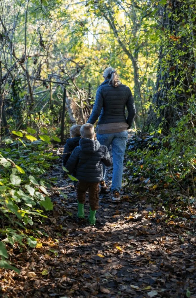 Erwachsene und zwei Kinder auf einem schmalen Waldweg