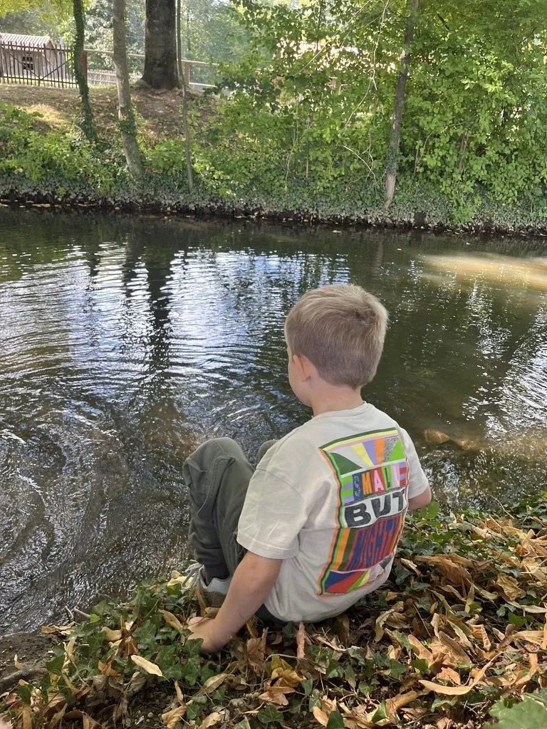 Junge sitzt am Ufer und schaut aufs Wasser
